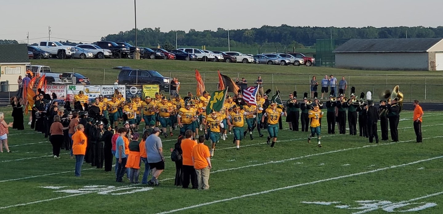 The football team storming the field, people dressed in orange in memory of Mr. McCulloch