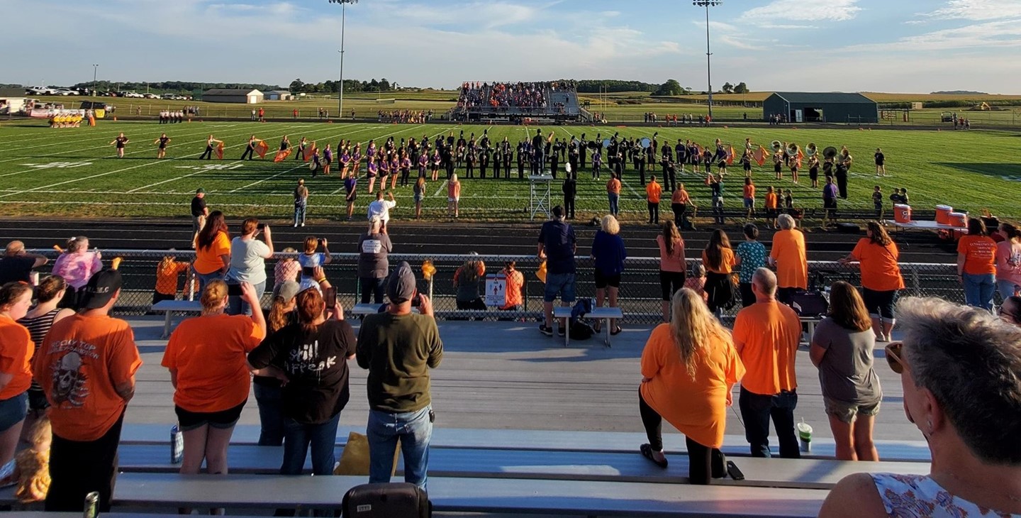 Band playing on the football field, orange in memory of Mr. McCulloch